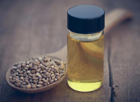 cbd-oil-in-a-bottle-next-to-a-wooden-spoon-filled-with-hemp-seeds